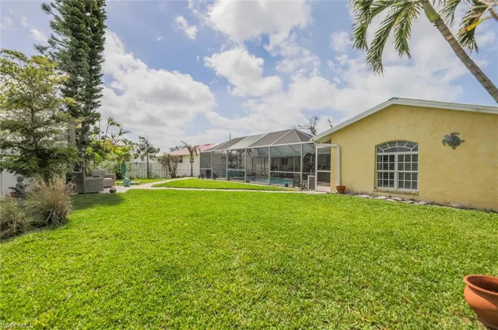 View of yard featuring a pool, fence, and glass enclosure