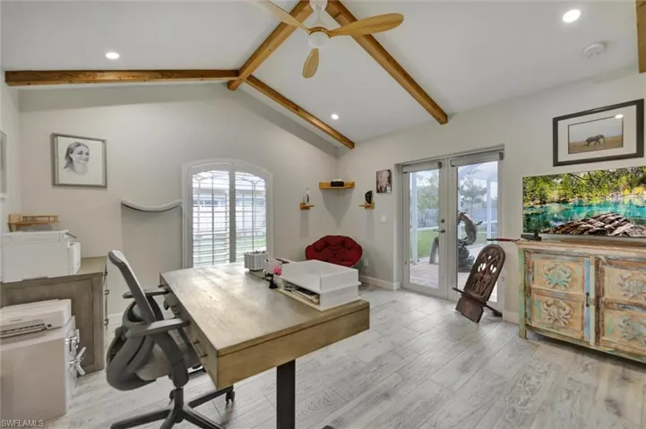 Office with a ceiling fan, light wood-style floors, lofted ceiling with beams, and a healthy amount of sunlight