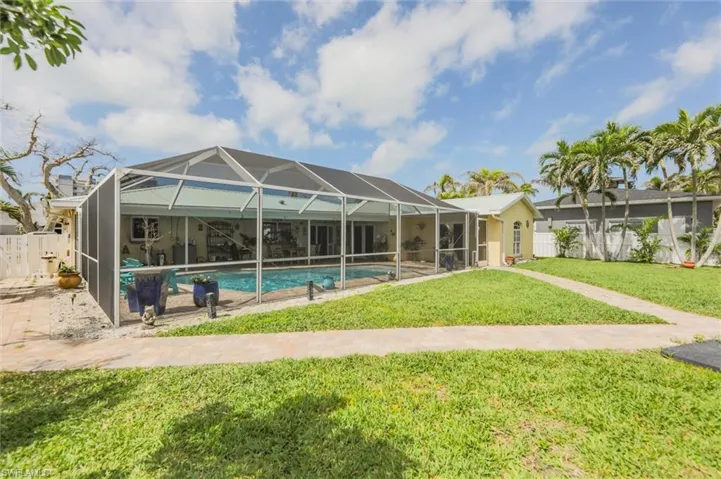Rear view of house featuring a lanai, a fenced in pool, fence, and a lawn