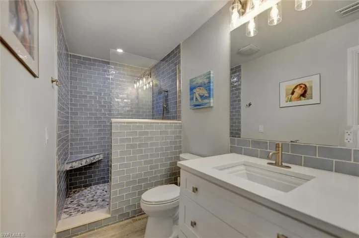 Full bathroom with visible vents, toilet, tiled shower, and vanity