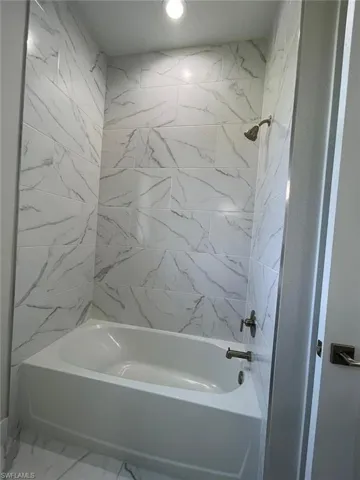 Bathroom with tile flooring and tiled shower / bath combo