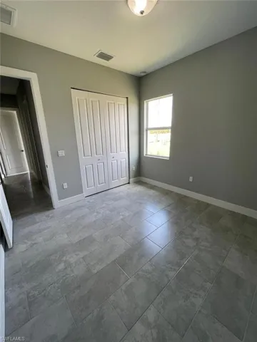 Unfurnished bedroom featuring dark tile floors and a closet