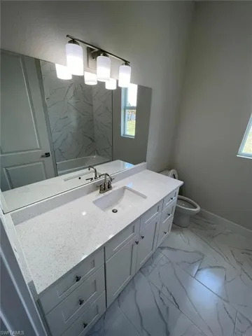 Bathroom featuring tile flooring, vanity with extensive cabinet space, toilet, and plenty of natural light