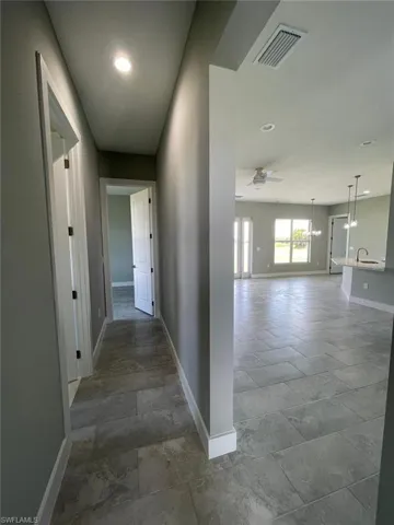 Corridor featuring sink and dark tile flooring