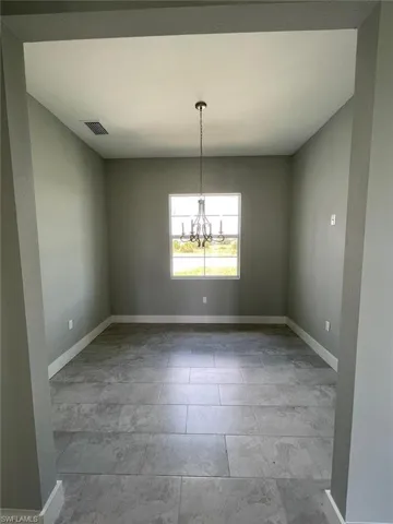 Empty room featuring a chandelier and tile floors