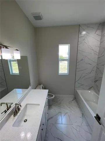 Bathroom featuring tile flooring, toilet, and vanity with extensive cabinet space