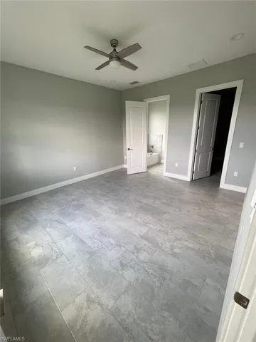 Unfurnished bedroom with tile flooring, connected bathroom, and ceiling fan
