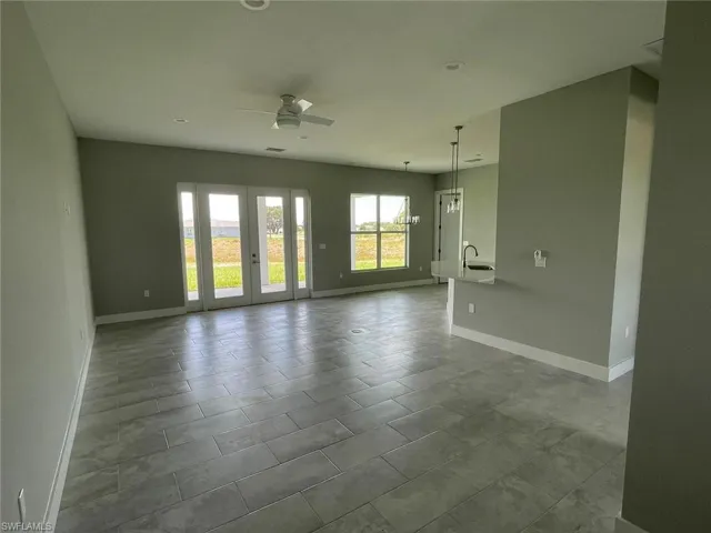 Tiled empty room featuring sink, ceiling fan, and french doors