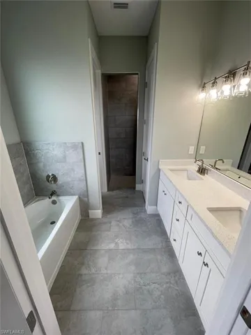 Bathroom with tile floors, a bathing tub, and double sink vanity
