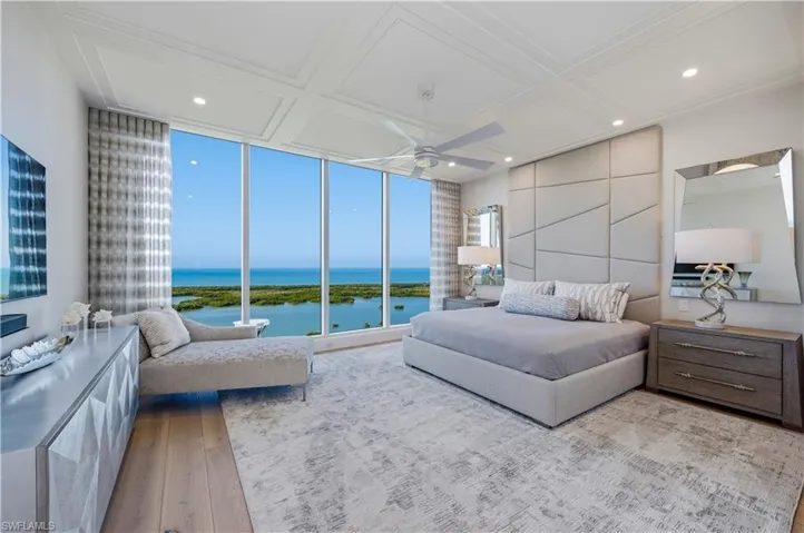 Bedroom with a water view, coffered ceiling, light wood-type flooring, a ceiling fan, and floor to ceiling windows