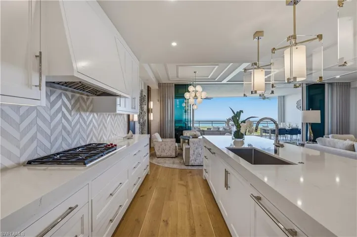 Kitchen with white cabinetry, light stone countertops, light wood-style flooring, and stainless steel gas stovetop