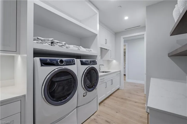 Laundry area with light wood-style flooring, independent washer and dryer, cabinet space, and recessed lighting