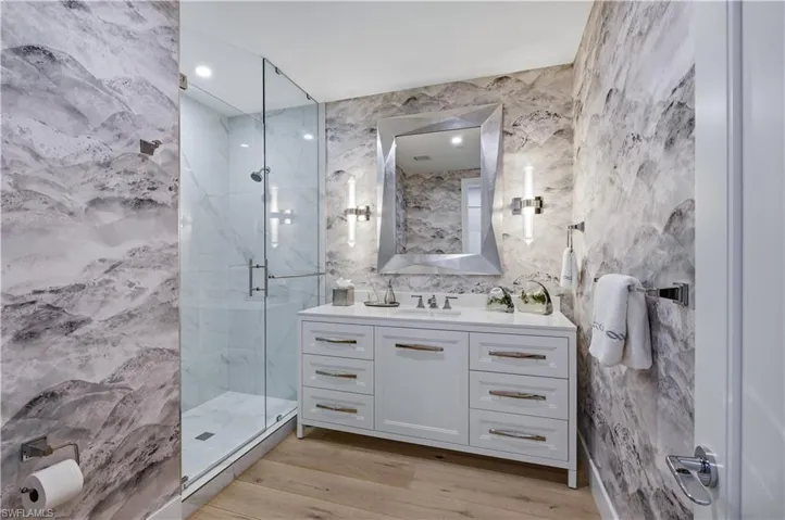 Full bath featuring vanity, tile walls, a marble finish shower, recessed lighting, and light wood finished floors