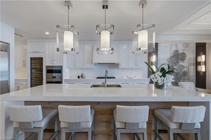 Kitchen featuring a kitchen bar, white cabinetry, and light stone counters