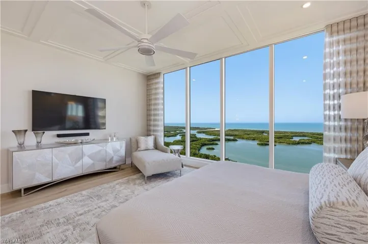 Bedroom with expansive windows, wood finished floors, and ceiling fan