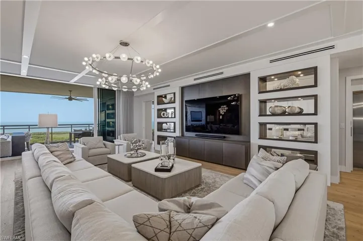Living area with hanging lights, light wood-style flooring, built in shelves, ceiling fan, and expansive windows