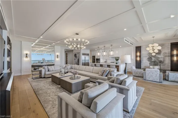 Living room with a chandelier, light wood-style flooring, and coffered ceiling