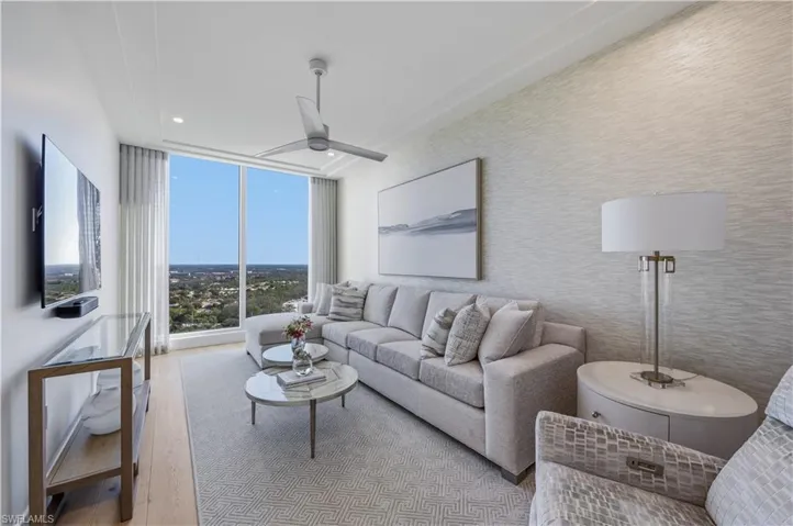Living area with floor to ceiling windows, a ceiling fan, and light wood-style floors