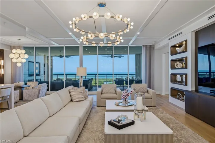 Living room with a chandelier, expansive windows, and light wood-style flooring
