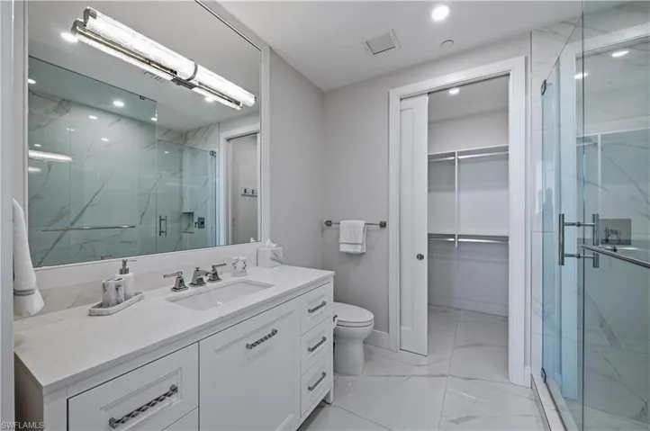 Bathroom with vanity, light marble finish flooring, a walk in closet, a marble finish shower, and recessed lighting