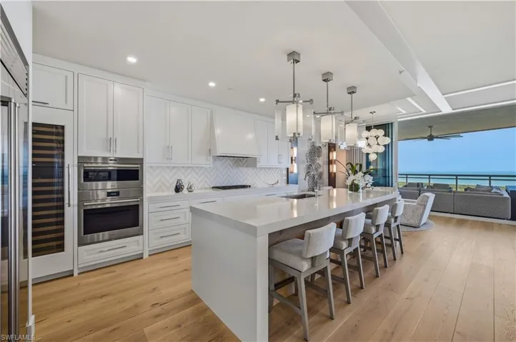 Kitchen featuring pendant lighting, white cabinetry, a breakfast bar, light wood-style flooring, and floor to ceiling windows