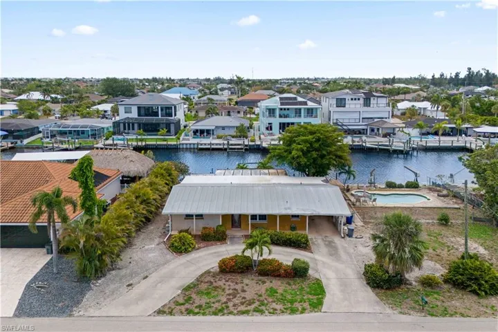 A stunning aerial shot revealing the entire layout, including the house, pool, dock, and lush surroundings.
