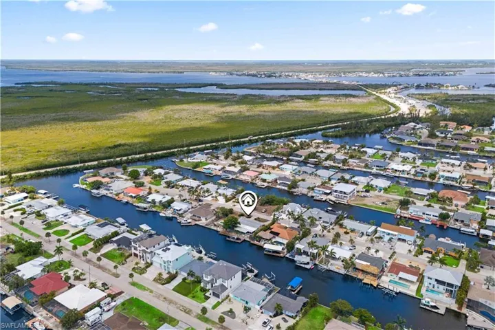 The expansive aerial view highlights the generous lot size, with the home at the center, the pool as a focal point, and the dock offering quick access to the canal to open water.