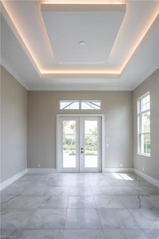 Spare room with french doors, a tray ceiling, and crown molding