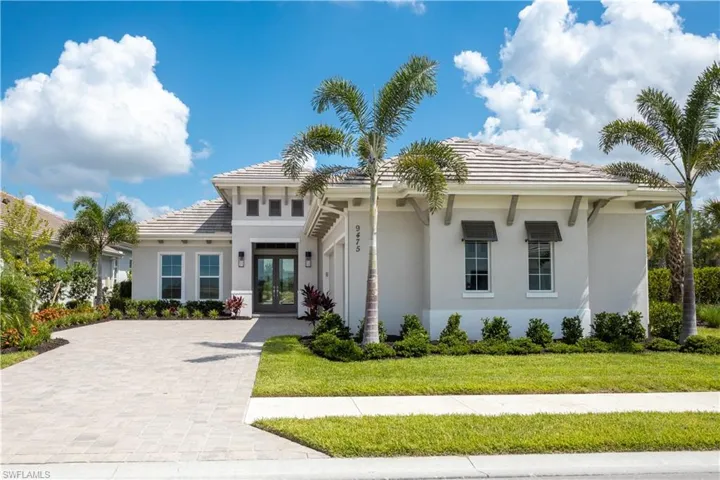 View of front of home featuring french doors, stucco siding, a tiled roof, driveway, and a front yard