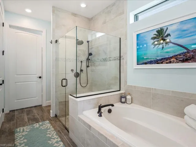 Primary Bathroom featuring a spacious glass enclosed shower and bath with dual vanities
