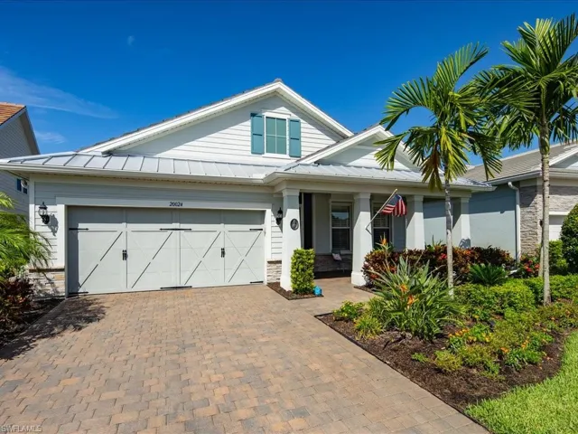 View of front facade featuring a garage, custom landscaping and a covered front porch sitting area