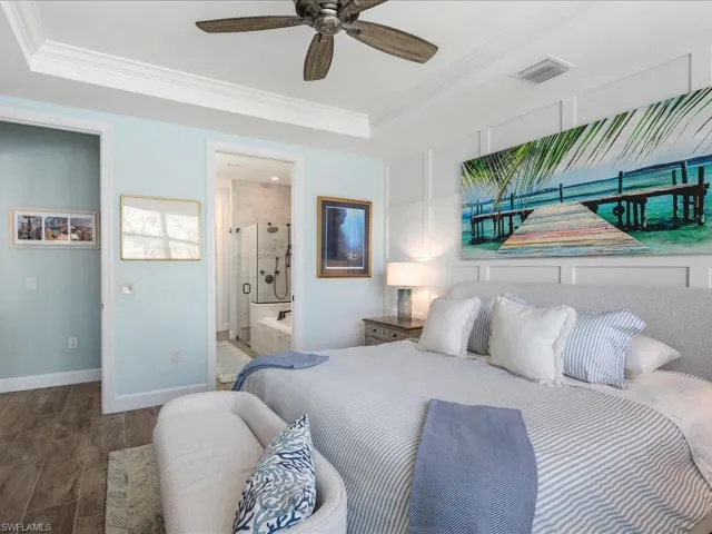 Primary Bedroom featuring ensuite bath, ceiling fan, custom wood detail, and ornamental molding