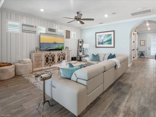 Great room featuring plenty of natural light, shiplap feature wall, and crown molding