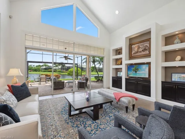 Living room featuring ceiling fan, a water view, built in features, high vaulted ceiling, and hardwood / wood-style flooring
