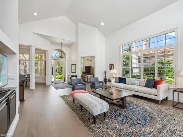 Living room featuring high vaulted ceiling, hardwood / wood-style flooring, and decorative columns