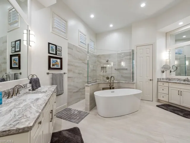 Primary bathroom featuring dual vanities, tile floors, large walk-in shower and a soaking tub