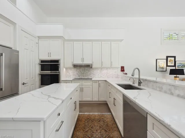 Kitchen with white cabinetry, sink, pantry and stainless steel appliances