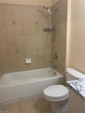 Bathroom featuring a white bathtub, ceramic wall tiling with accent details, and a white toilet