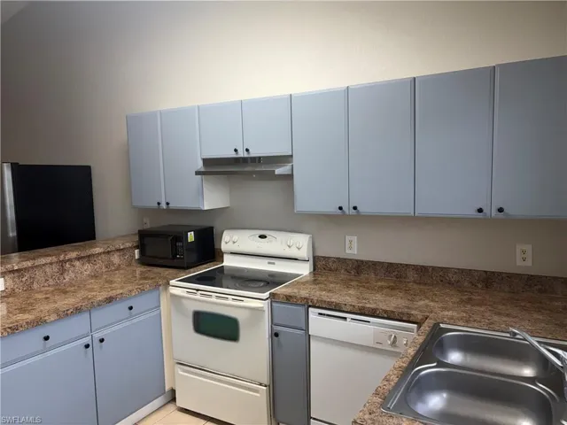 Kitchen featuring light blue cabinetry with black knob hardware, mottled brown countertops, a stainless steel double basin sink, white electric range, and a white dishwasher
