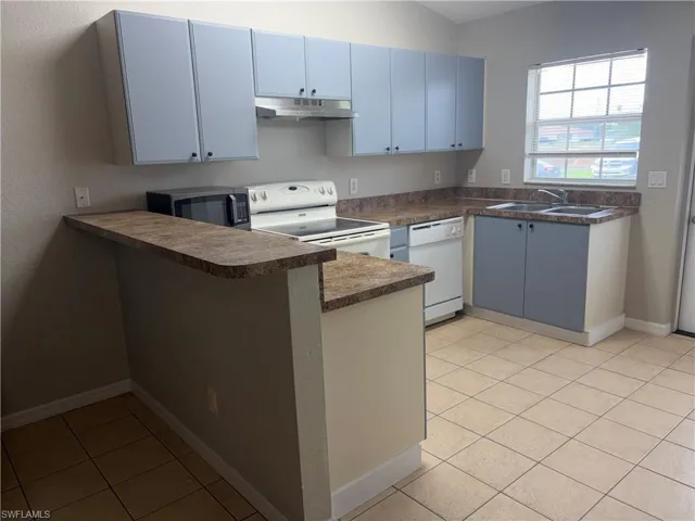 Kitchen featuring blue cabinetry with black hardware, laminate countertops, and a double basin stainless steel sink