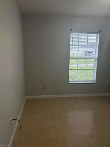 Neutral tone painted walls and a single window with horizontal blinds