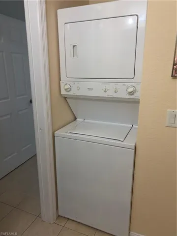 Stackable white laundry appliances with tile flooring