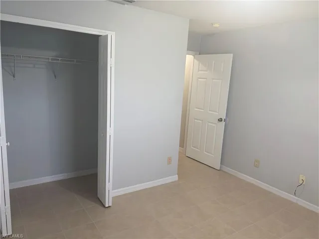 Bedroom featuring neutral-toned tile flooring, light gray wall paint, and white baseboards