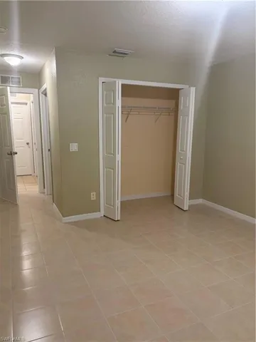 Spacious room featuring neutral-toned ceramic tile flooring, a bi-fold closet with wire shelving, and light-toned wall paint