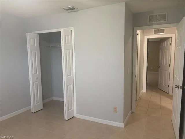 Interior space featuring neutral wall paint, tile flooring, white baseboards, and a bi-fold closet with wire shelving