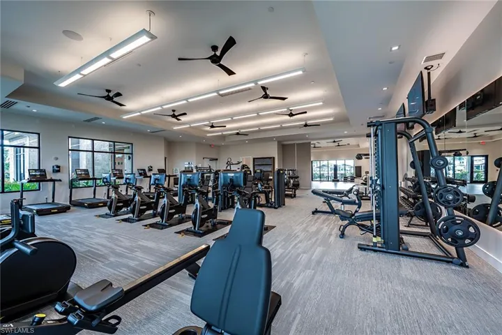 Gym with ceiling fan and light colored carpet