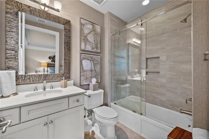Bathroom with shower / bath combination with glass door, vanity, and radiator
