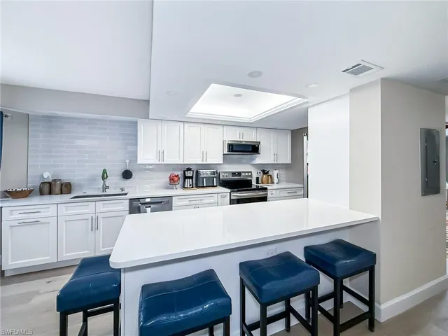 Kitchen with a breakfast bar area, sink, white cabinets, and appliances with stainless steel finishes