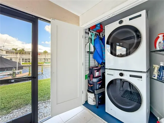 Clothes washing area with a water view, stacked washer / dryer, and light tile patterned floors