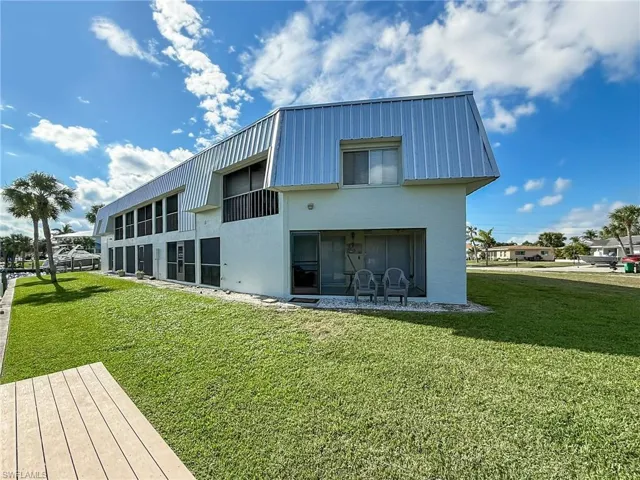 Back of property with metal roof, a yard, and stucco siding